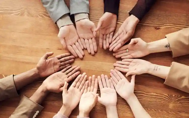 Diverse hands of different skin tones held together in a circle