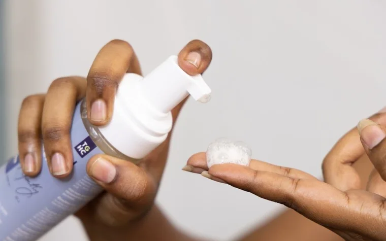 Hand pumping white foaming cleanser onto fingertips