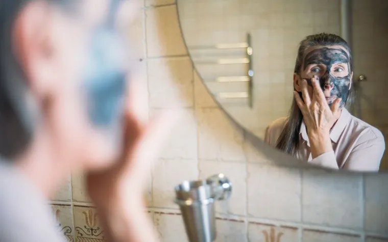 A mature woman applying moisturizing cream to her face