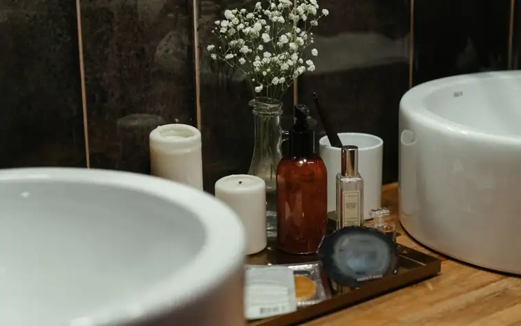 An arrangement of skincare bottles and candles on a shelf