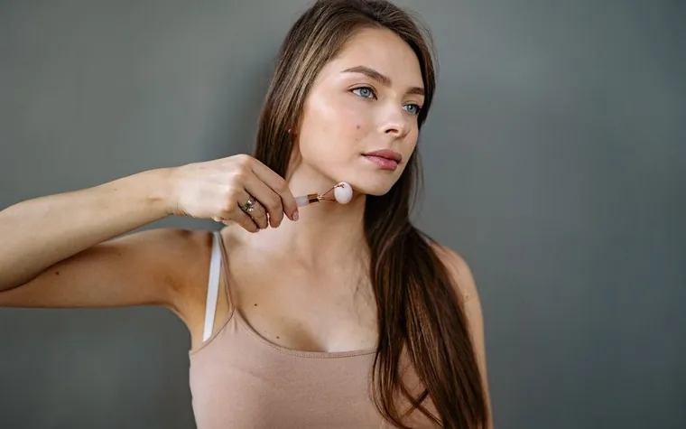 Woman using a gua sha tool on her cheek