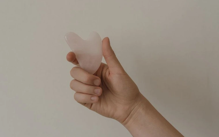Hand holding a rose quartz gua sha tool