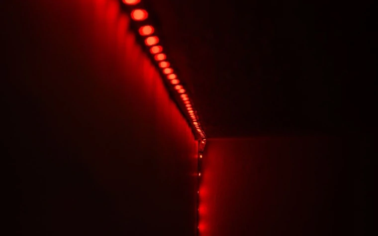 Close-up of a red LED light strip glowing along a dark corner