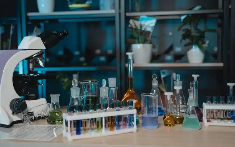 A microscope and laboratory glassware on a research bench