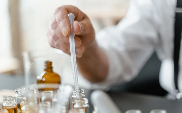 A person measuring liquid into small bottles at a laboratory bench