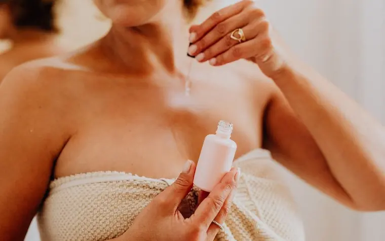 A woman applying serum from a dropper to her skin